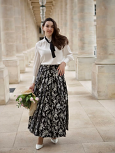 a lady wears a black floral printed maxi skirt with a white blouse
